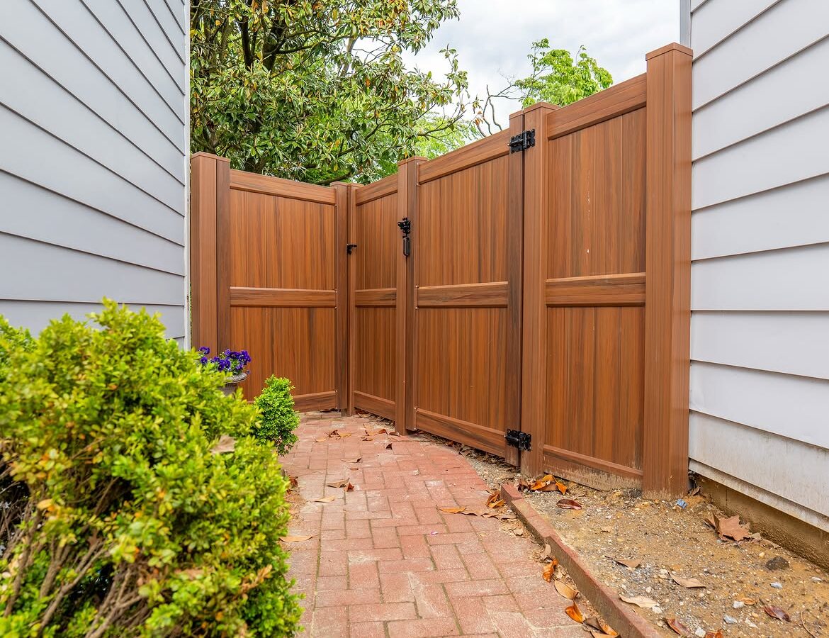 Gate detail of brown vinyl privacy fence and paver patio in North Wilmington, DE