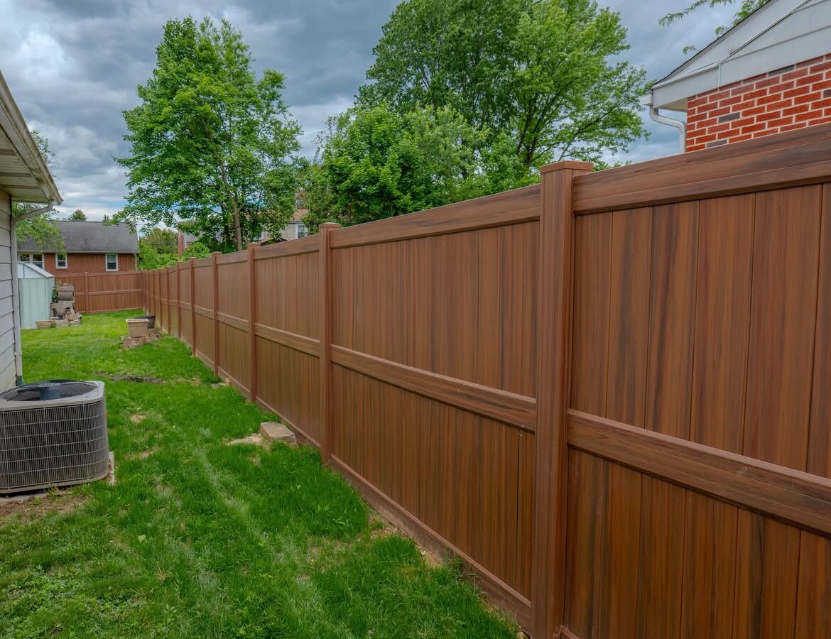 Corner detail of brown vinyl privacy fence and paver patio in North Wilmington, DE
