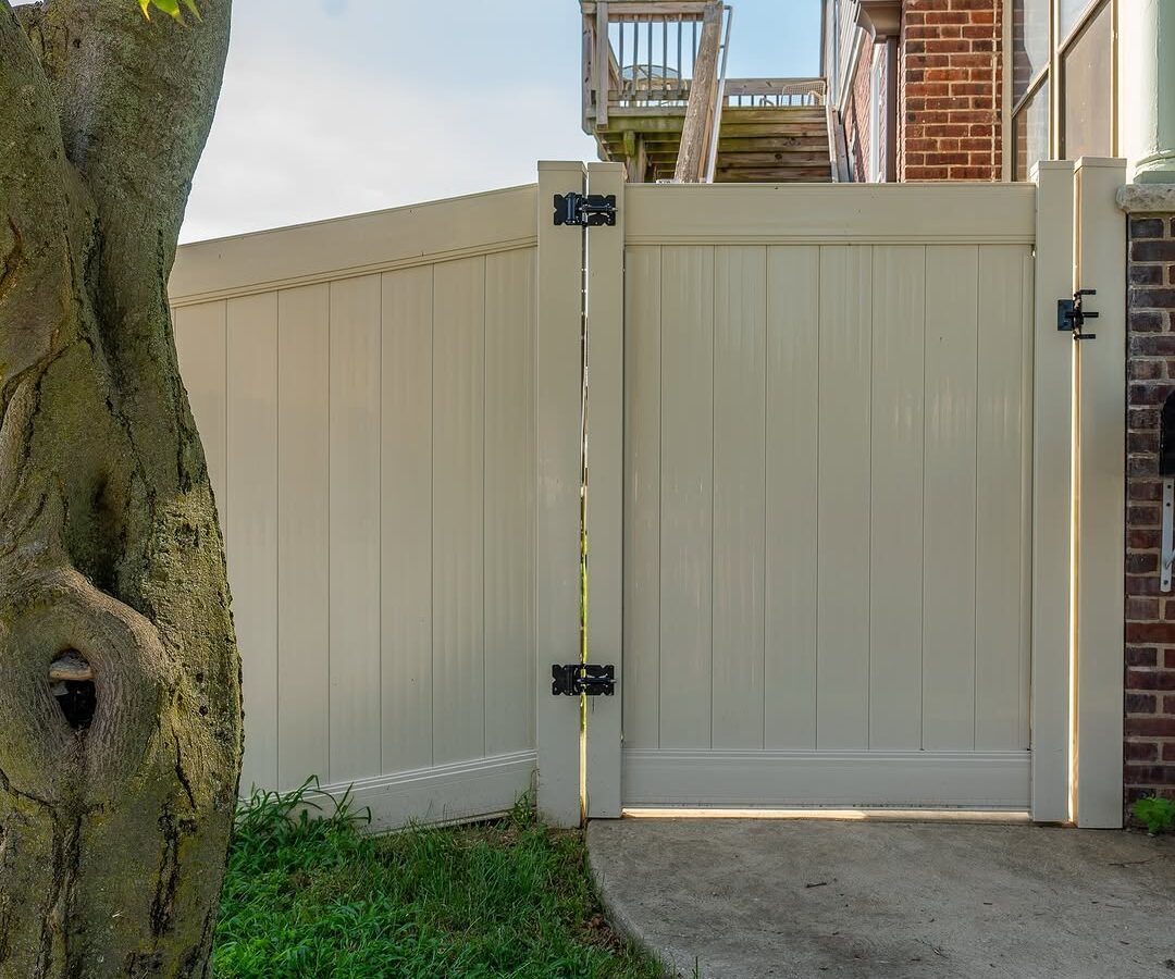 Gate detail of cream vinyl privacy fence in Delaware