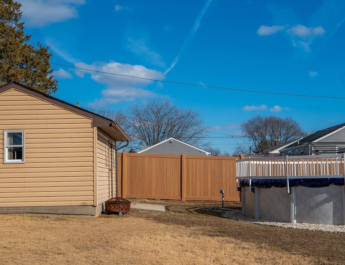 Angled view of light tan wood grain vinyl fence in Aston, PA
