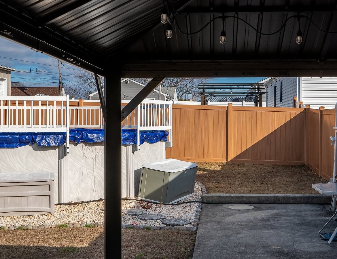 Property line view of light tan wood grain vinyl fence in Aston, PA