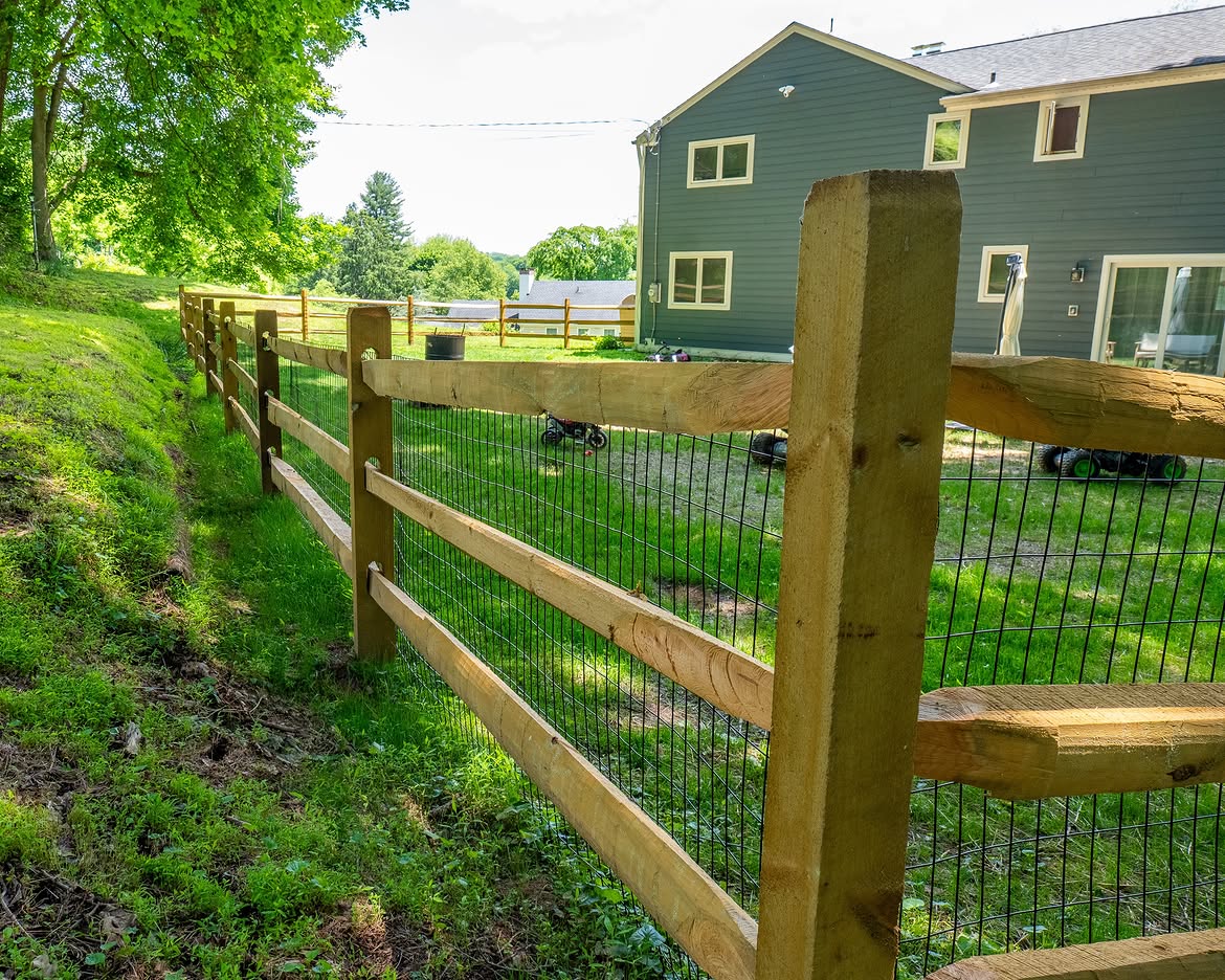 Side view of wood post-and-rail fence with wire mesh in Delaware