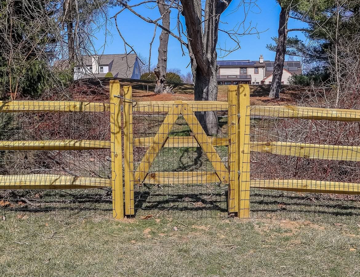 Gate detail of split rail fence with wire backing in Delaware