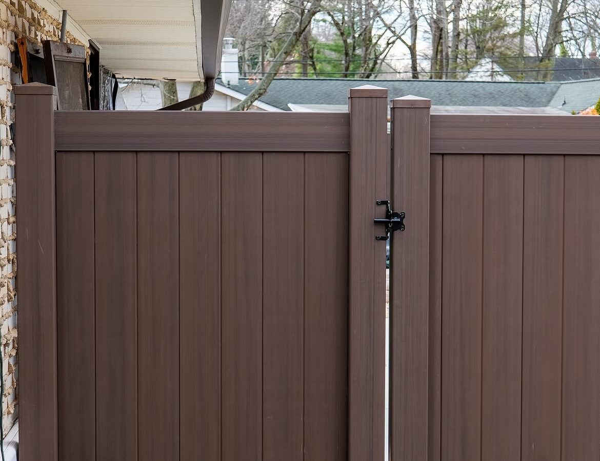 Gate detail of tan and brown wood grain vinyl fence in Delaware