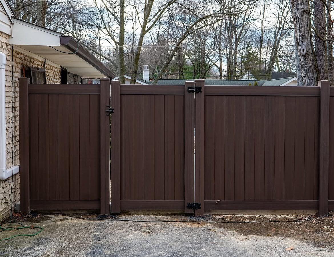 Gate detail of tan and brown wood grain vinyl fence in Delaware