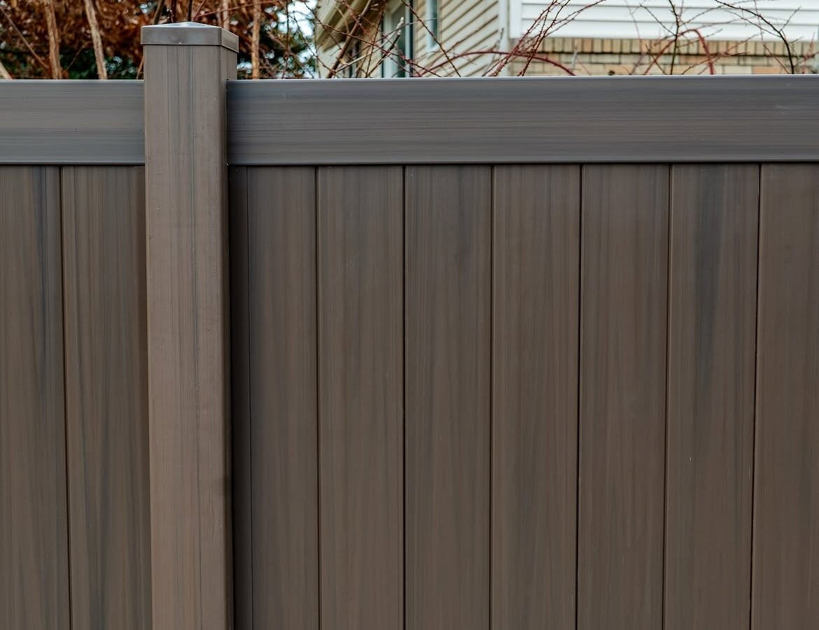 Angled view of tan and brown wood grain vinyl fence in Delaware