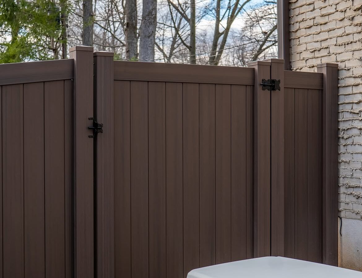 Gate detail of tan and brown wood grain vinyl fence in Delaware
