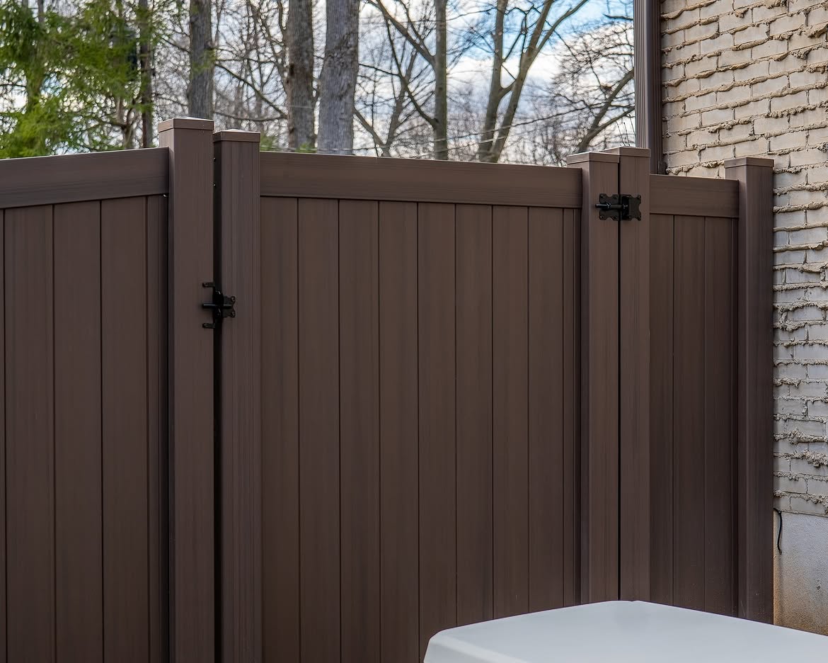 Gate detail of tan and brown wood grain vinyl fence in Delaware