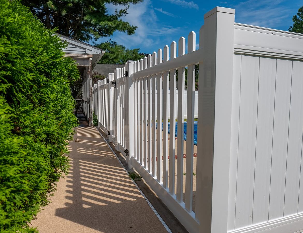 Property line view of white vinyl pool fence in Delaware
