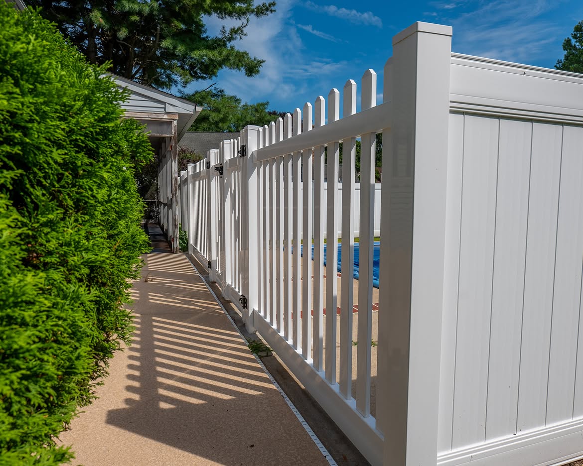 Property line view of white vinyl pool fence in Delaware