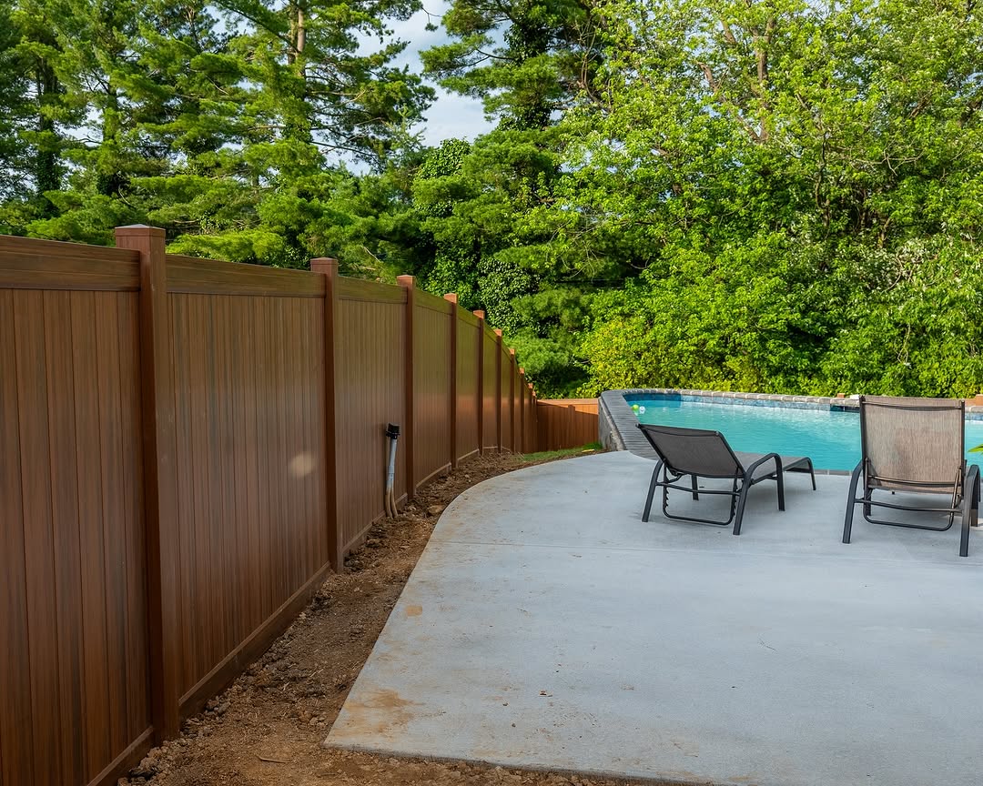 Full view of wood grain vinyl fence and pool patio in Delaware