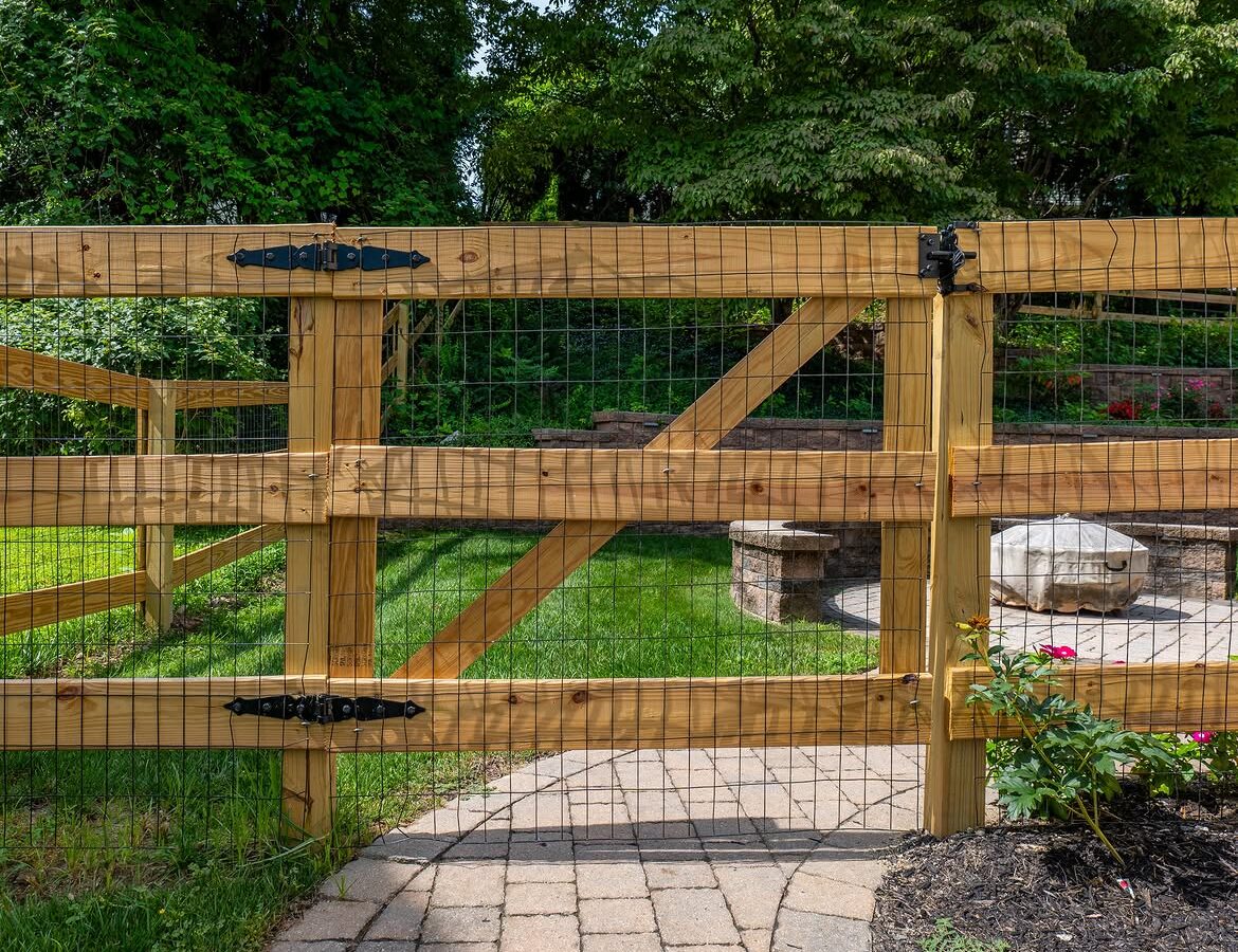 Gate detail of wood post-and-rail fence, paver patio and retaining wall in Delaware