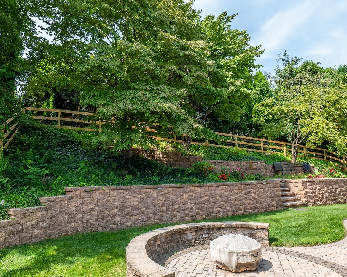 Corner detail of wood post-and-rail fence, paver patio and retaining wall in Delaware