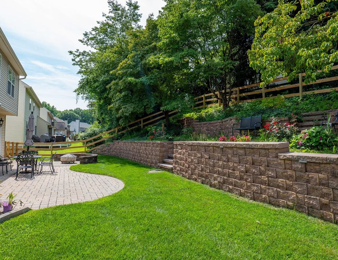 Wide view of wood post-and-rail fence, paver patio and retaining wall in Delaware