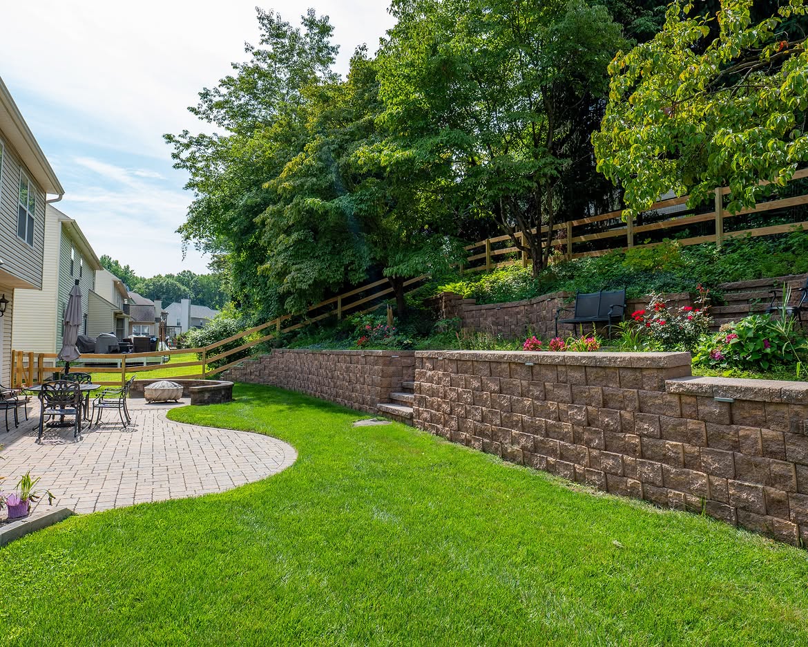 Wide view of wood post-and-rail fence, paver patio and retaining wall in Delaware