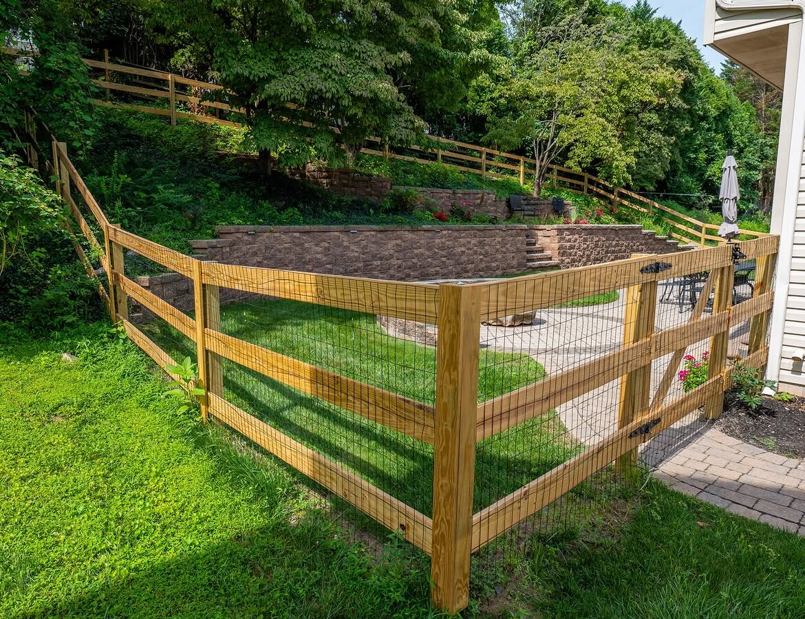 Rear yard view of wood post-and-rail fence, paver patio and retaining wall in Delaware